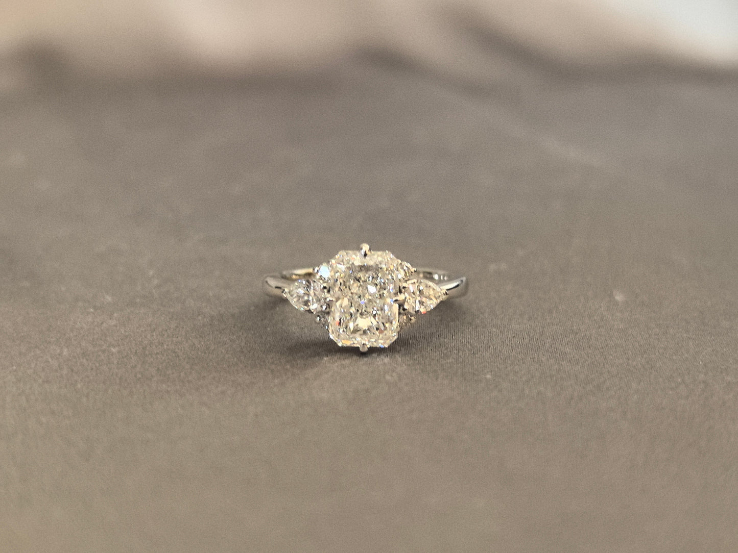 Three-stone emerald-cut lab diamond engagement ring - Pear-shaped sidestone - 4-Prong Set